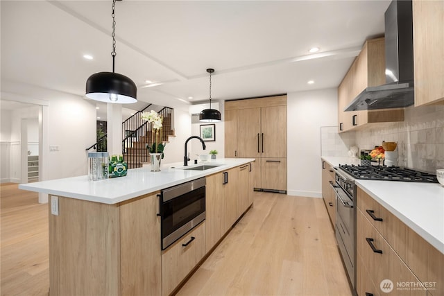 kitchen with wall chimney exhaust hood, light countertops, a kitchen island with sink, and stainless steel appliances