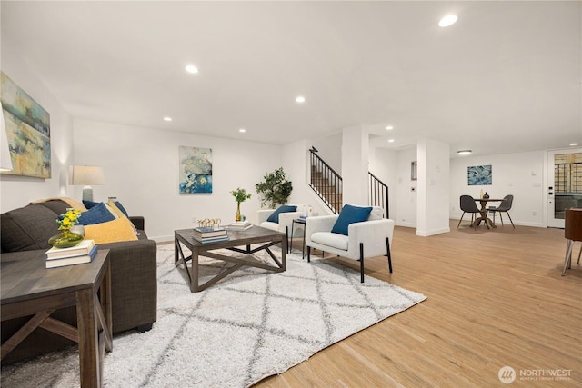 living room with light wood finished floors, stairs, baseboards, and recessed lighting