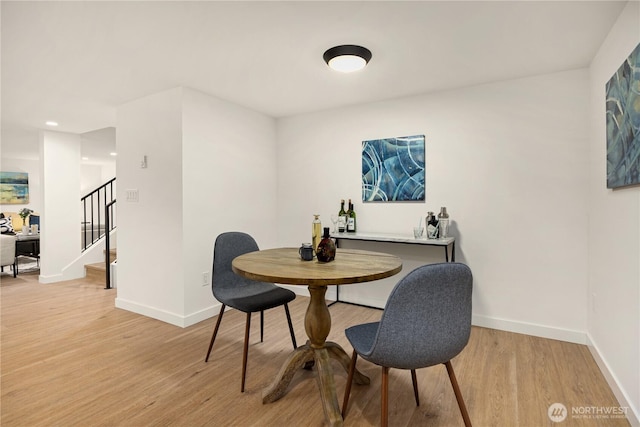 dining space with stairway, light wood-type flooring, and baseboards