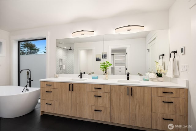 bathroom with a spacious closet, double vanity, a sink, and a shower stall