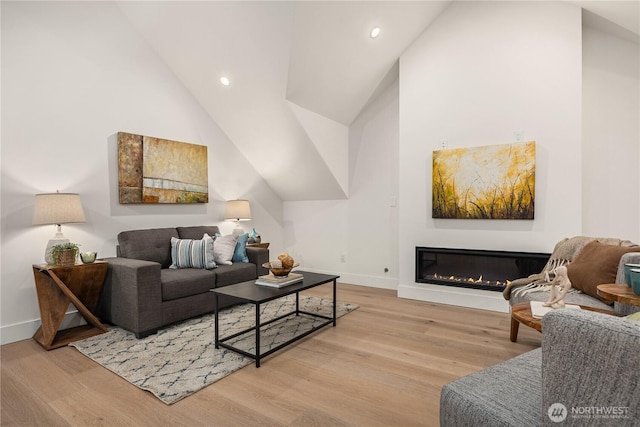 living area with light wood-type flooring, recessed lighting, baseboards, and a glass covered fireplace