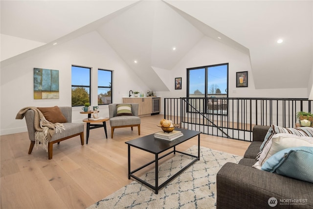 living room with high vaulted ceiling, wine cooler, baseboards, and light wood finished floors