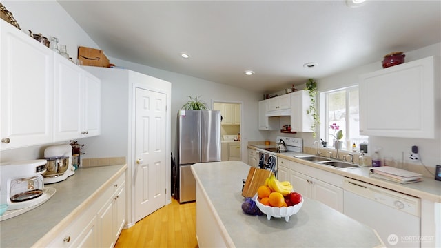 kitchen with light countertops, white cabinetry, a sink, light wood-type flooring, and white appliances