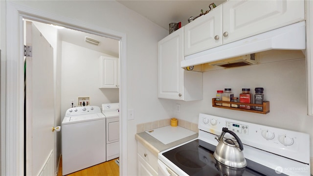 laundry room with visible vents, light wood finished floors, washer and clothes dryer, and cabinet space