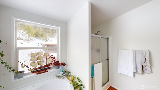 bathroom with a stall shower and a garden tub