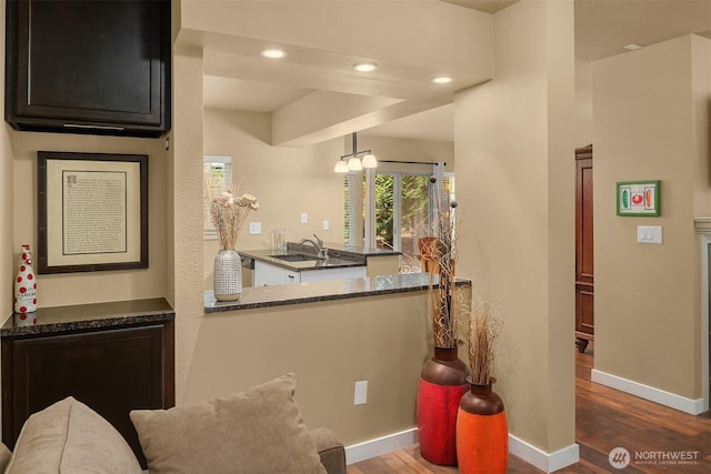 interior space with a sink, recessed lighting, baseboards, and wood finished floors