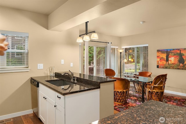 kitchen with visible vents, a peninsula, plenty of natural light, a sink, and white cabinetry