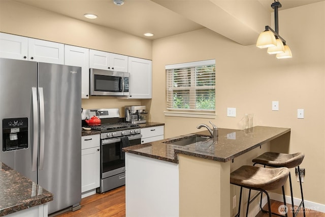 kitchen featuring a sink, stainless steel appliances, a peninsula, and white cabinets