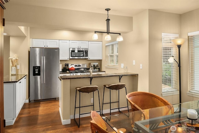 kitchen featuring plenty of natural light, appliances with stainless steel finishes, a peninsula, and white cabinets