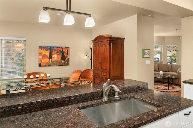 kitchen featuring dark stone countertops, pendant lighting, and a sink