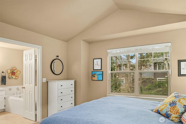 bedroom with connected bathroom and lofted ceiling