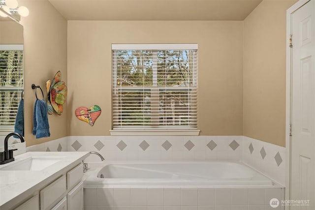 bathroom with a healthy amount of sunlight, a bath, and vanity