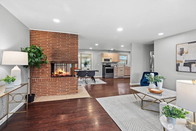 living area featuring recessed lighting, a fireplace, dark wood-type flooring, and baseboards