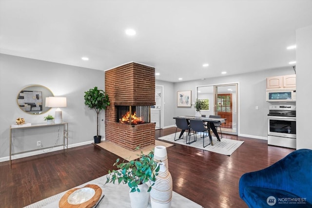 living room with recessed lighting, a fireplace, baseboards, and wood finished floors