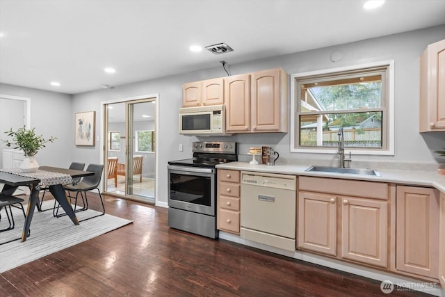 kitchen with white appliances, dark wood-style floors, visible vents, a sink, and light brown cabinetry