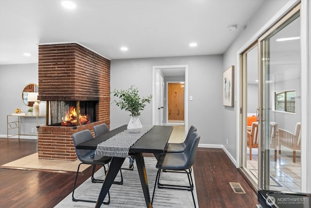 dining area with visible vents, a fireplace, baseboards, and wood finished floors