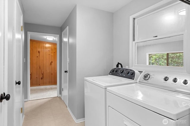 clothes washing area with laundry area, light floors, baseboards, and washer and clothes dryer