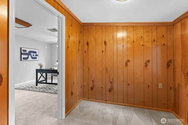 hallway with carpet flooring, baseboards, visible vents, and wood walls