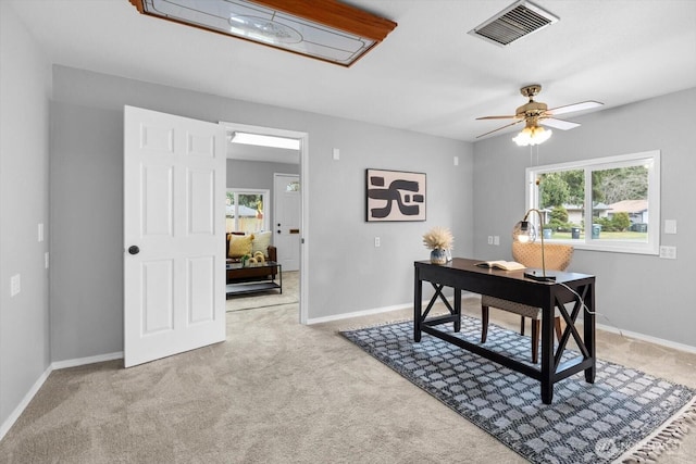 carpeted home office featuring visible vents, baseboards, and ceiling fan