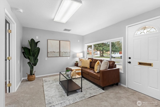 carpeted living area featuring visible vents and baseboards