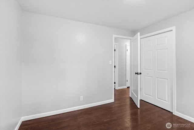 unfurnished bedroom featuring a closet, baseboards, and dark wood-style floors