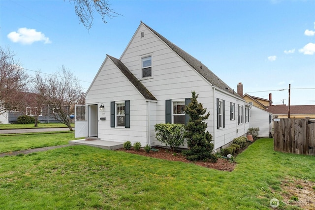 exterior space featuring roof with shingles, a front lawn, and fence