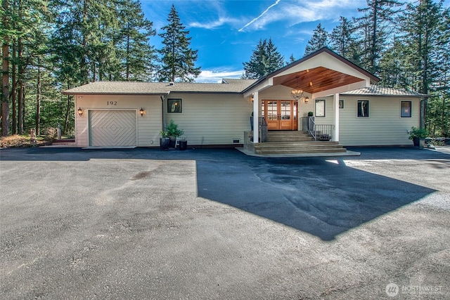 ranch-style house featuring driveway, an attached garage, and french doors