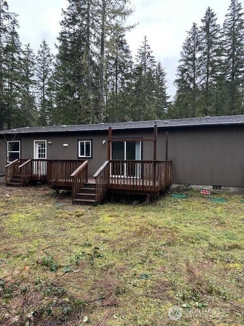 back of house featuring a lawn and a wooden deck