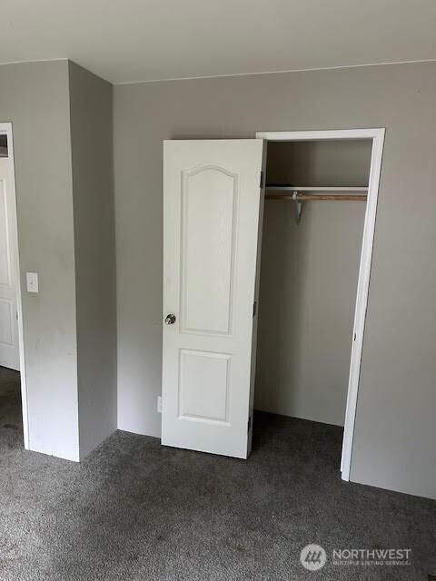 unfurnished bedroom featuring a closet and dark carpet