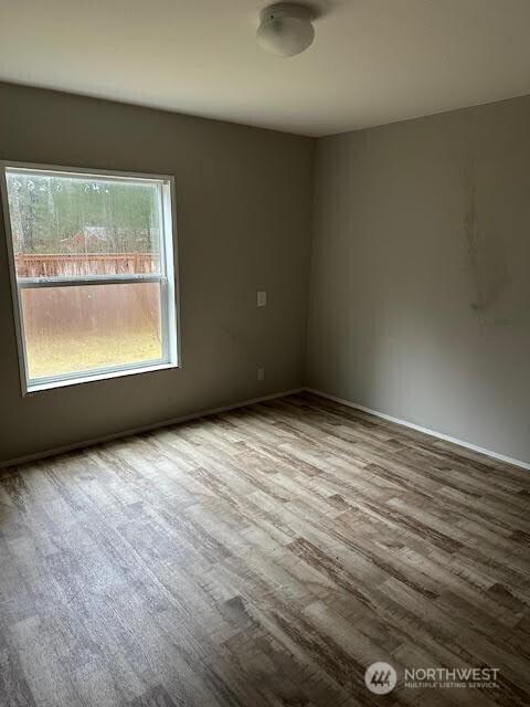 unfurnished room with baseboards and wood finished floors