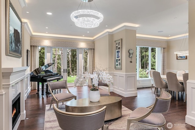 interior space with french doors, crown molding, a decorative wall, wainscoting, and a chandelier