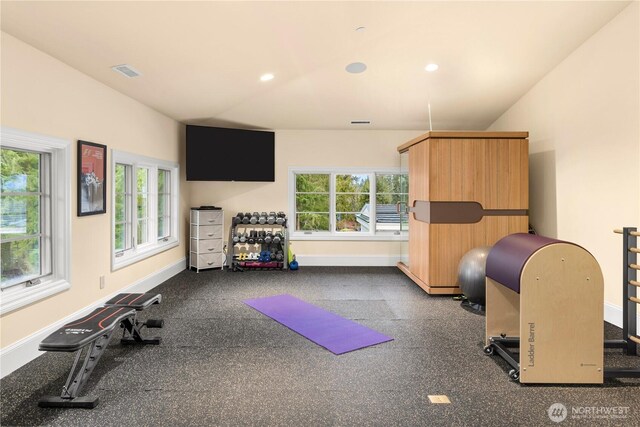 exercise room featuring vaulted ceiling, visible vents, and baseboards