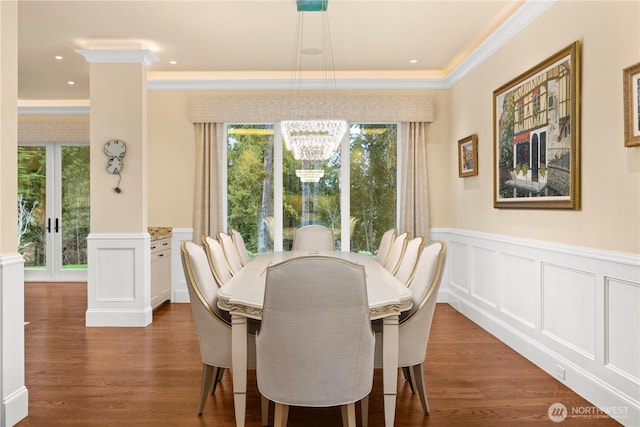 dining space featuring a healthy amount of sunlight, a notable chandelier, wood finished floors, and wainscoting