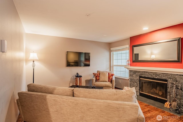 living area with recessed lighting, wood finished floors, and a stone fireplace