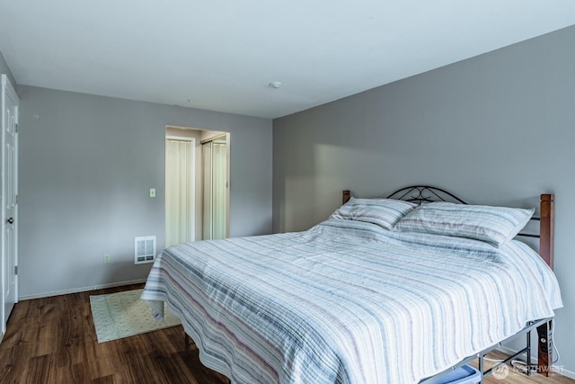 bedroom with baseboards, visible vents, and wood finished floors