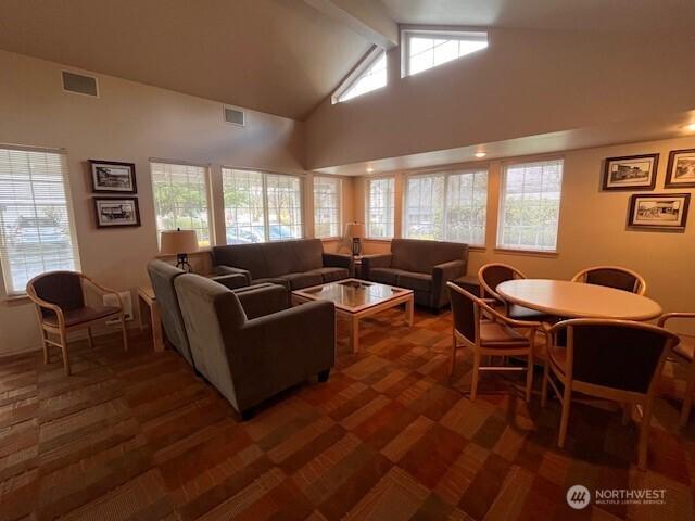 living area with a healthy amount of sunlight, visible vents, and beam ceiling