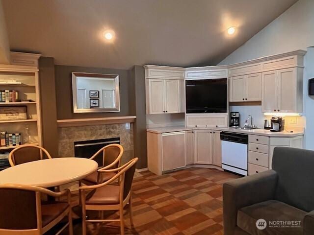 kitchen with white dishwasher, white cabinetry, a fireplace, and light countertops