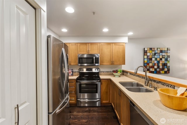 kitchen featuring light stone counters, recessed lighting, dark wood-type flooring, a sink, and appliances with stainless steel finishes