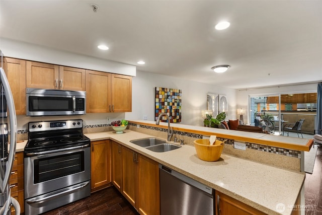 kitchen featuring recessed lighting, appliances with stainless steel finishes, dark wood-type flooring, a sink, and a peninsula