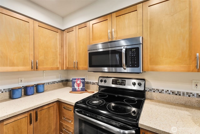 kitchen with appliances with stainless steel finishes and light stone counters