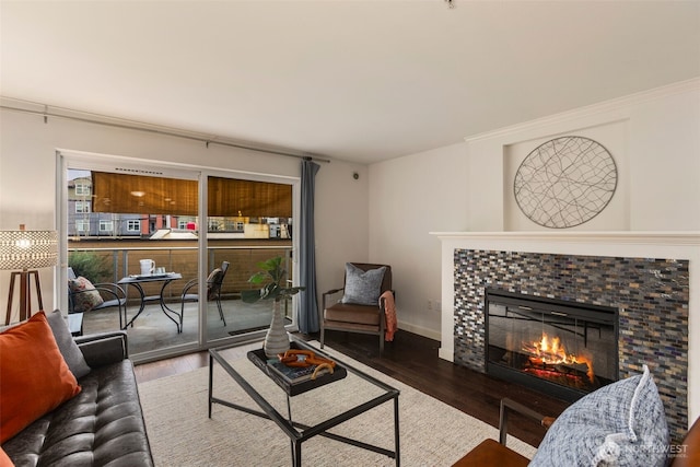 living room with a tiled fireplace, hardwood / wood-style flooring, and baseboards