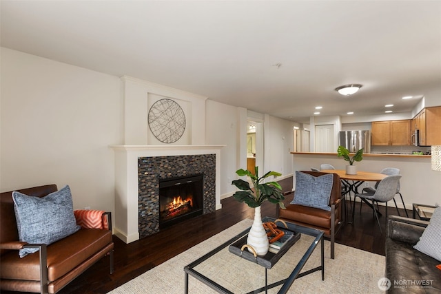 living area featuring a tiled fireplace, baseboards, wood finished floors, and recessed lighting