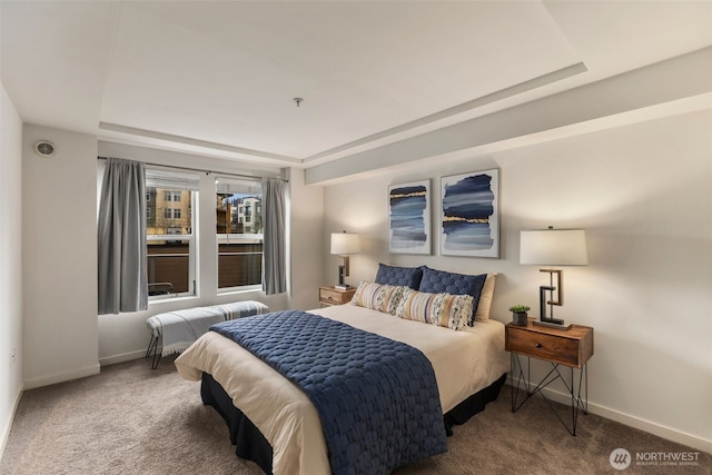 carpeted bedroom featuring a tray ceiling and baseboards