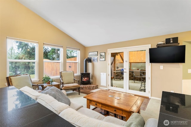 living room with lofted ceiling, a wood stove, carpet flooring, and french doors