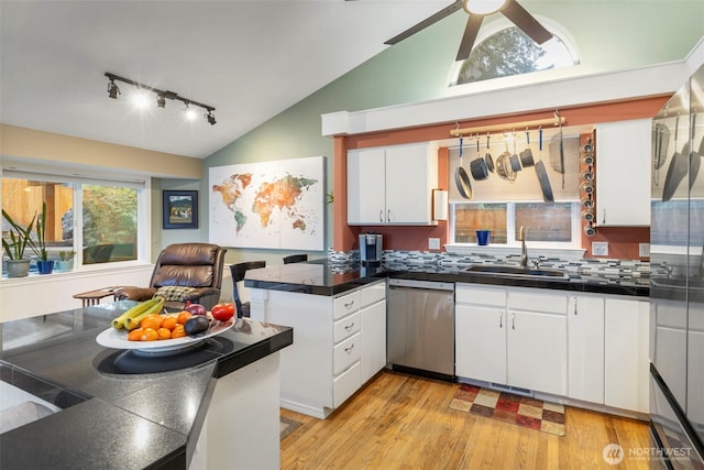 kitchen featuring lofted ceiling, appliances with stainless steel finishes, light wood-style floors, white cabinetry, and a sink