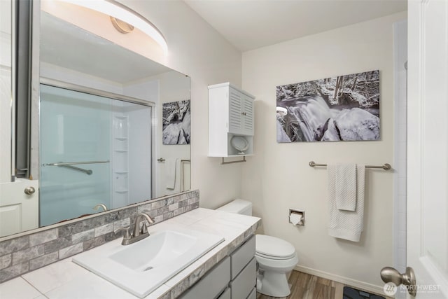 full bathroom with baseboards, toilet, wood finished floors, a shower with shower door, and vanity