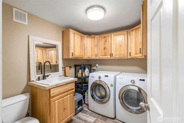 washroom featuring laundry area, washing machine and dryer, visible vents, and a sink