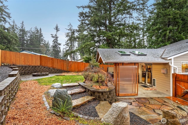 view of yard with a patio area, a fenced backyard, and an outdoor structure