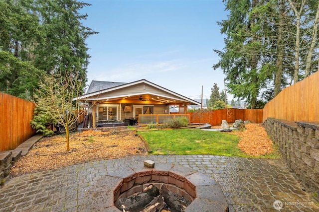 rear view of property with a patio area, a fenced backyard, a fire pit, and a ceiling fan