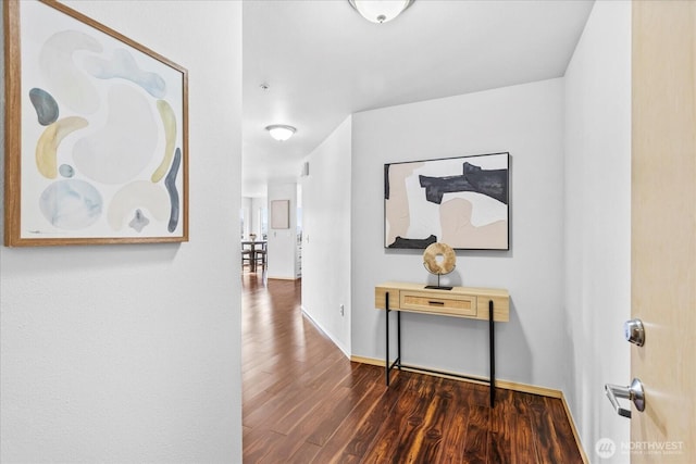 corridor featuring baseboards and wood finished floors